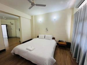a bedroom with a white bed and a ceiling fan at Aijal Club in Āīzawl