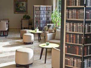 een bibliotheek met tafels, stoelen en boeken bij Hotel Les Oliviers in Fayence