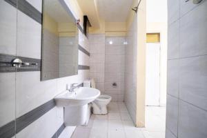 a white bathroom with a sink and a toilet at Capital comfort Hotel Ambala Rd in Nairobi