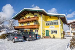 a yellow building with cars parked in the snow at Haus Roswitha in Flachau