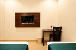 a room with two beds and a tv on the wall at Hotel BKC Suite in Mumbai