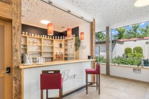 a bar with two red chairs and a window at Hotel Zur Post in Ismaning