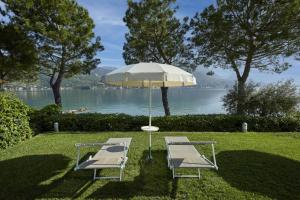 two chairs and a table and an umbrella in the grass at Park Hotel Casimiro in San Felice del Benaco +40 photos