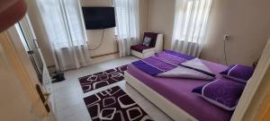a bedroom with a purple bed and a chair at AMY APARTMAN in Tuzla