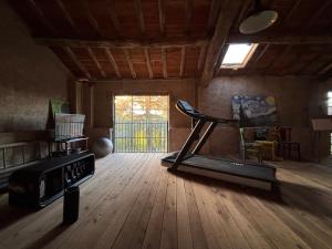 a gym with a treadmill in a room with wood floors at Locanda SottolaLuna in Viano