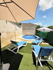 a patio with two chairs and an umbrella and a pool at Casa Rural Hidalgo II in Alcolea de Calatrava