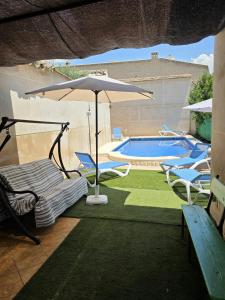 a patio with an umbrella and chairs and a pool at Casa Rural Hidalgo II in Alcolea de Calatrava