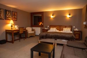 a bedroom with a bed and a desk and a couch at Logis Hotel les Sapins in Le Ménil