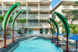 a swimming pool with umbrellas in front of a building at Grand Mercure Krabi Ao Nang in Ao Nang Beach