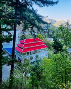 a building with a red roof in the midst of trees at Redapple Rooms in Murree