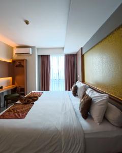 ein Hotelzimmer mit einem großen weißen Bett und Kissen in der Unterkunft Loji Hotel in Solo + 40 Fotos