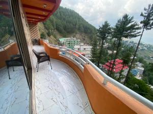 a balcony with two chairs and a view of a mountain at Redapple Rooms in Murree +23 photos
