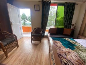 a bedroom with a bed and a chair and a window at Redapple Rooms in Murree