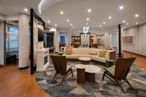 a living room with a couch and a table and chairs at SpringHill Suites by Marriott Buffalo Airport in Williamsville
