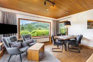 a living room with a table and chairs and a large window at Ferienhaus Rothaarblick mit Sauna in Schmallenberg