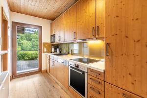 a kitchen with wooden cabinets and a large window at Ferienhaus Rothaarblick mit Sauna in Schmallenberg