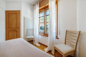 a bedroom with a bed and two chairs and a window at Alla Loggia dell'Imperatore in Levico Terme