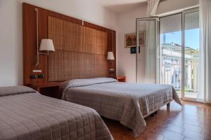 a hotel room with two beds and a large window at Villa Lucia in Caorle