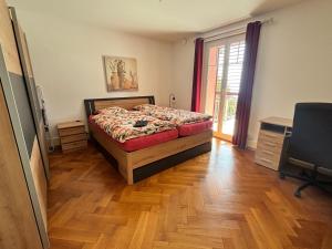 a bedroom with a bed and a wooden floor at Chez Carole (4 pièces) in Neuchâtel