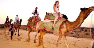a group of people riding on camels in the desert at Marwar Desert Camp Sam Jaisalmer in Sām