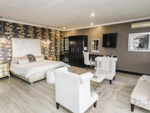 a bedroom with a bed and chairs and a table at Altissimo Guesthouse in Bloemfontein