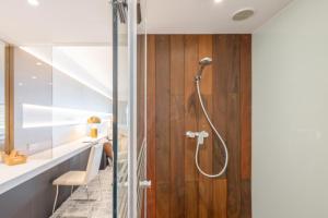 a shower in a bathroom with a wooden wall at Sitges Suites - Premium in Sitges +15 photos