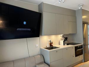 a kitchen with white cabinets and a tv on the wall at Perfect cosy living in Stockholm