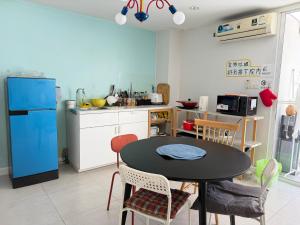 a kitchen with a table and a blue refrigerator at silom lestay纯女民宿 in Yan Nawa