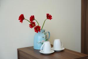 a blue vase with red flowers sitting on a table at Reka Homestay in Thôn Dương Phẩm