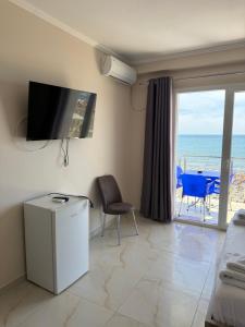 a living room with a tv and a balcony with the ocean at Hotel Fredi Shengjin in Shëngjin