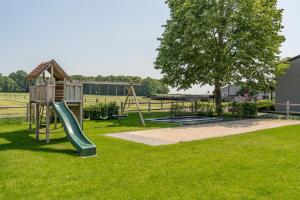 a playground with a slide and a tree at B&B De Bergvallei in Oedelem