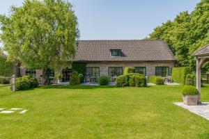 a house with a green yard in front of it at B&B De Bergvallei in Oedelem