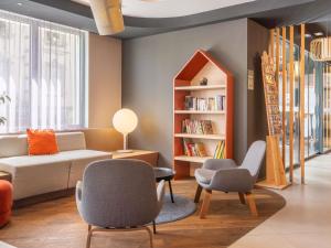 a living room with a couch and two chairs and a book shelf at Novotel Suites Colmar Centre in Colmar