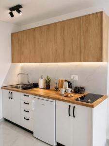 a kitchen with white cabinets and a wooden counter top at The River Studio Beli in Podgorica