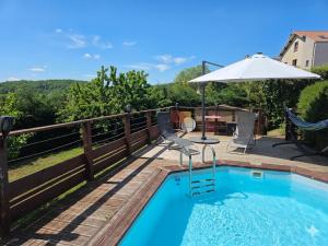 a swimming pool with an umbrella and a patio at Châtel-guyon : Appart cosy avec place de parking et piscine près des thermes in Châtel-Guyon
