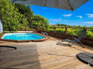a deck with a swimming pool and a chair and an umbrella at Châtel-guyon : Appart cosy avec place de parking et piscine près des thermes in Châtel-Guyon