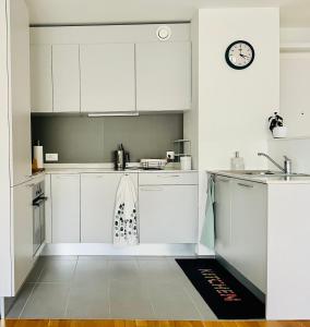 a kitchen with white cabinets and a clock on the wall at Modern 1-Bedroom Retreat in Lausanne