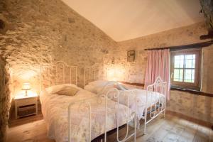 a bedroom with a white bed in a stone wall at GITE FOUR A PAIN 4 pers in Bon-Encontre