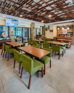 ein Restaurant mit Holztischen und grünen Stühlen in der Unterkunft Loji Hotel in Solo