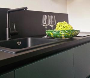a kitchen sink with a bowl of flowers and wine glasses at Fischerhof in Cortaccia