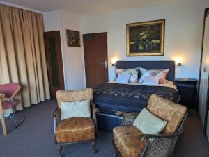 a hotel room with a bed and two chairs at Haus Kiel Wohnung Mühlenberg in Altenau