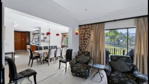 a living room with chairs and a dining room at Konrad 8 in Uvongo Beach