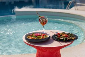 a plate of food and a drink on a table next to a pool at THB Naeco Ibiza - Adults Only in San Antonio Bay