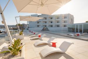 a row of white chairs and an umbrella on a building at THB Naeco Ibiza - Adults Only in San Antonio Bay