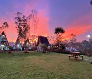 a house with a picnic table in a field with a sunset at Cozzy Artana Cabin in Palayangan