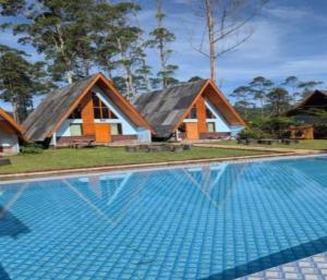 a house with a swimming pool in front of it at Cozzy Artana Cabin in Palayangan