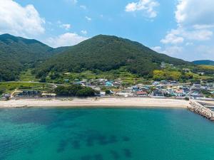 an aerial view of a beach with a town and mountains at Namhae Padosori Oceanview Pension in Namhae