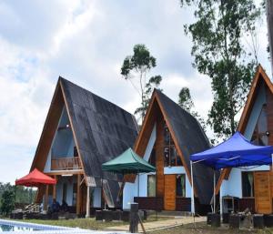 a house with a black roof and some umbrellas at Cozzy Artana Cabin in Palayangan