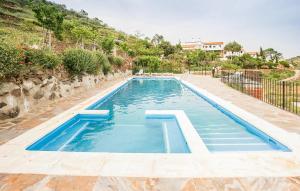 a swimming pool with blue water in front of a house at La Curiosa in Laroya