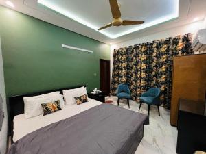 a bedroom with a bed with a green wall and two chairs at Karachi Inn in Karachi